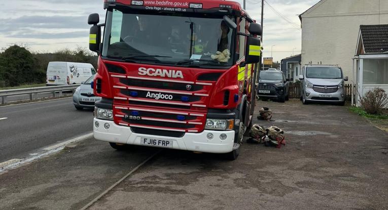 Fire engine on roadway outside house fire. 