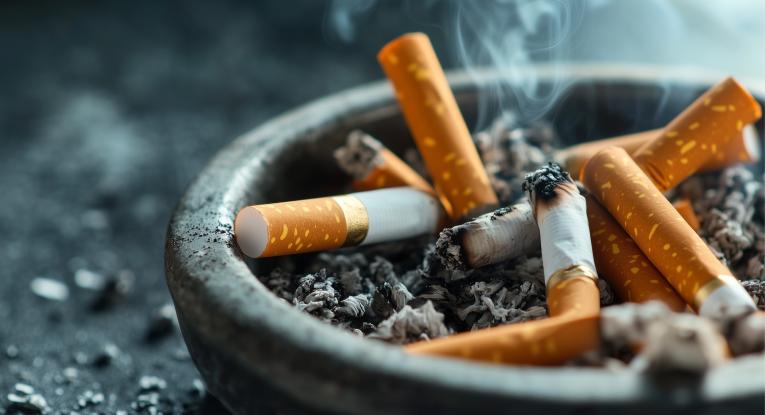 An ashtray with smoke rising from a discarded cigarette.